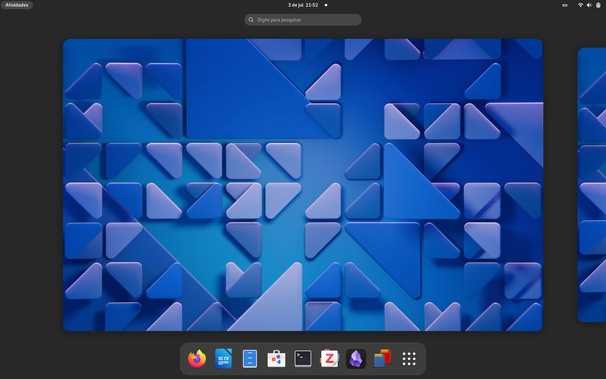 Captura de tela mostrando o panorama de atividades do GNOME 46, com seu plano de fundo com triângulos azuis com gradientes suaves. Nenhum aplicativo está aberto. Na borda inferior, o "dash" tem os aplicativos: Firefox, LibreOffice Writer, Arquivos, Gerenciador de Programas, Terminal, Zotero, Obsidian e Rapid Photo Downloader, além do símbolo para a lista de todos os aplicativos. Na borda superior, está escrito "Atividades" em vez de símbolos para as áreas de trabalho (o Gnome Shell 46 ainda não chegou, só os planos de fundo), há um pontinho de notificação ao lado da data e hora, e há um indicador de layout de teclado ("en") ao lado dos símbolos da área de notificação.