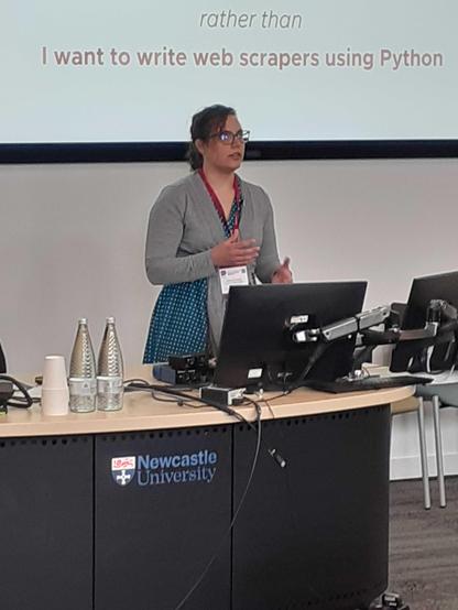 Gabrielle Scroeder standing at a lectern giving her talk at RSECon24.