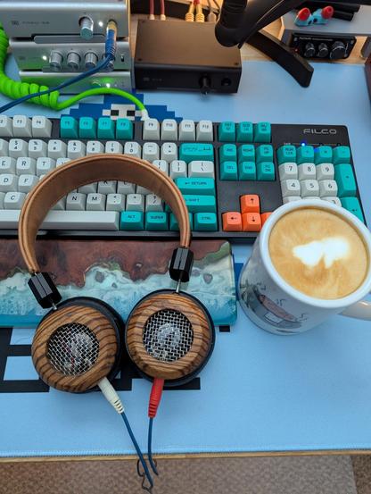 Heavily modified Grado SR80e Headphones next to a latte in front of a keyboard and blue desk mat
