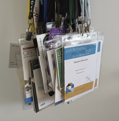 Collection of badges from conferences and other events hanging from lanyards, at front is the badge from Everything Open 2025