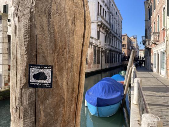 The FSFE’s sticker “There’s no cloud, just someone else’s computer” stuck on a wooden boat-parking pole, in a Venetian canal. Close-up of the previous photo.