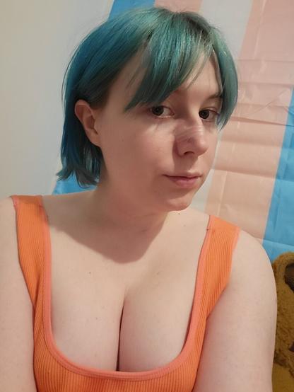 Revy with her blue hair tied back behind her ears.
She has no makeup 
She's wearing a orange singlet
And the borbs be borbin