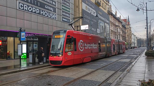Tramwaj Tramwajów Śląskich (dominujący kolor: czerwony) przed Galerią Katowicką, wśród miejskiej zabudowy.