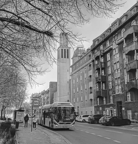 Autobus PKM Katowice (dominujący kolor: niby żółty, ale zdjęcie jest w czerni i bieli) w centrum Katowic. W tle wieża kościoła. Gdzieś w okolicy aresztu śledczego i ulicy Kopernika/Mikołowskiej.