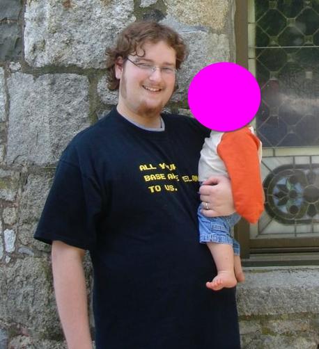 A photo of an obese man holding a child (whose face is redacted). Standing in front of a tourist trap "Castle" in New England, wearing an "All your base are belong to us" t-shirt