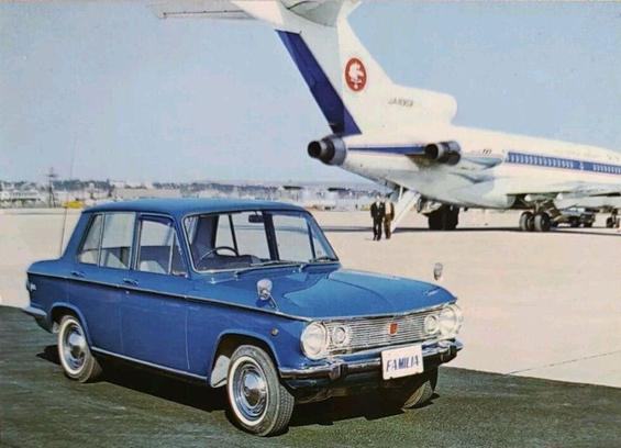 Upfront is a small economy car. In the back is the tail of the airplane with two men walking from the plane to the car. Small note - this plane would later crash.