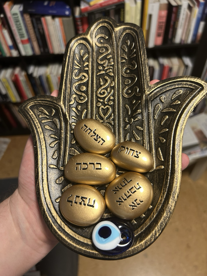 Eine mit Schriftzeichen verzierte Handschale mit goldenen Steinen und hebräischer Schrift.
