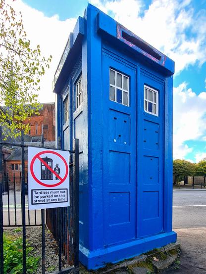 A sign posted next to a Glasgow police box saying Tardises must not be parked on this street at any time.