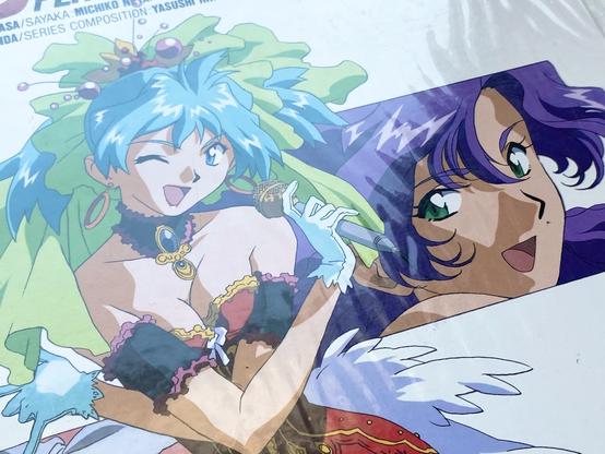 A closeup photo of the same cover, showing a detail of Miku and a portrait of another purple haired anime girl behind her.  Purple is the best color.