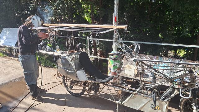 Welelder working on solar roof frame of solar bike.