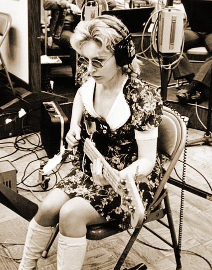 Carol Kay seated in the studio playing her bass guitar.