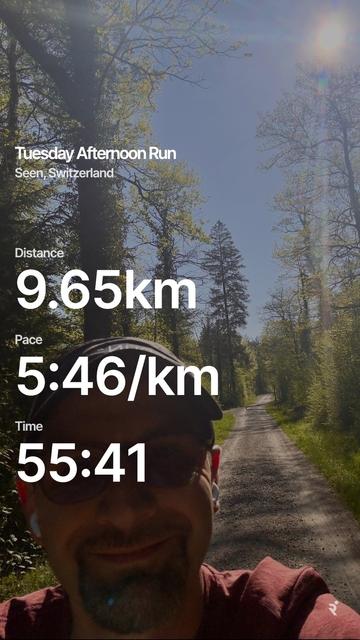 A man wearing sunglasses and a cap poses on a forest trail under a clear sky, with running statistics overlayed showing a distance of 9.65km, pace of 5:46/km, and time of 55:41.