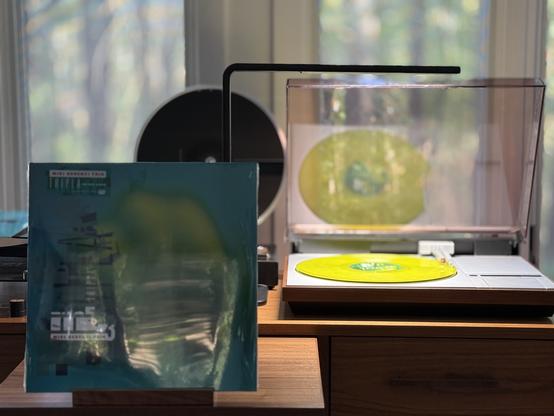 Miki Berenyi Trio - Triple LP cover.

On a teal background, a green blob.

The green LP plays on a vintage, restored Bang & Olufsen Beogram 4000 linear-tracking turntable to the right.