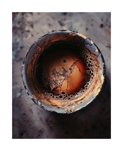A color photo showing an overhead view of a raku teacup filled with tea. Framed in white.