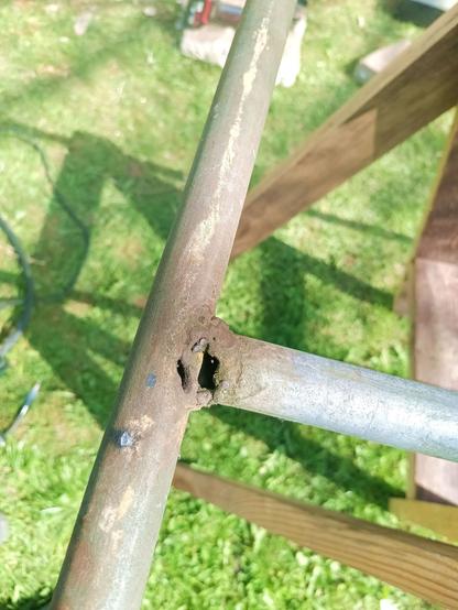 A typical "farm weld" from the previous folks, probably stick welded. Two  pieces of galvanized steel tube joined at 90 degree. A big gap is between them, held together with some very rough weld blobs. A second hole is burnt into one of the pipes. It held together anyways and if it didn't, it was just blobbed again.