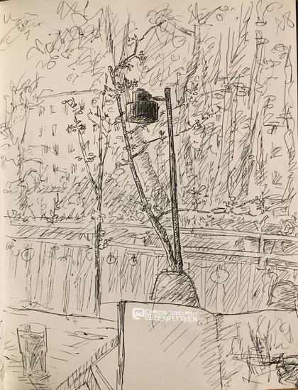 Black fineliner on paper

in the bottom right a sketchbook, laid out on legs. behind it a balcony parapet with plant pots and plants in it, in front of it thin little trees.  a table on the left, a glass on top of it. A lamp in the middle of the picture, darkest spot. In the background large trees and a block of flats.
