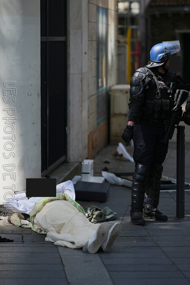 Un homme à la rue allongé sur le trottoir observe la tenue complète d'un CRS à côté de lui pendant les manifs du 1er mai à Nantes. Photos de Tonio