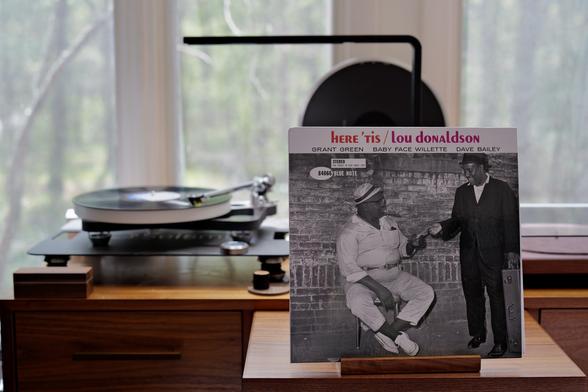 lou donaldson - here ‘tis LP cover.

A black and white photo of two musicians, one seated in white smoking a cigarg one standing in black with what looks to be a sax case, so I’m going to assume that’s Donaldson. The standing one is handing the seated one some money.

The black LP plays on a Rega NAIA turntable to the left.