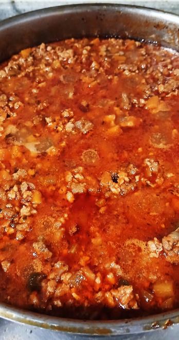 A steaming-hot frying pan of Bolognese sauce.