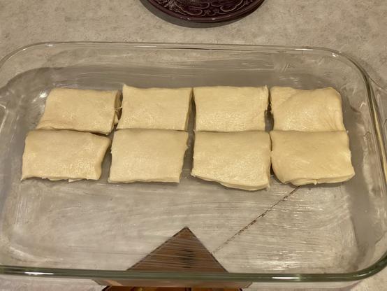 eight rectangular once-folded roll dough filling half of a 9 by 13 glass baking pan