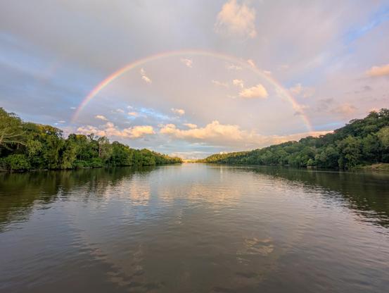 Rainbow over the Potomac with green trees on both banks reflecting in the water
