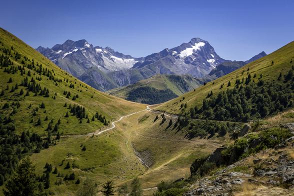 Mountain landscape of Alpe d'Huez in the morning on a summer day, under a bright blue sky.