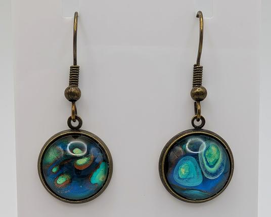 A pair of paint dip earrings: the settings are bronze, and the dipped cabochons are blue, copper, turquoise, and yellow with circular-esque shapes.