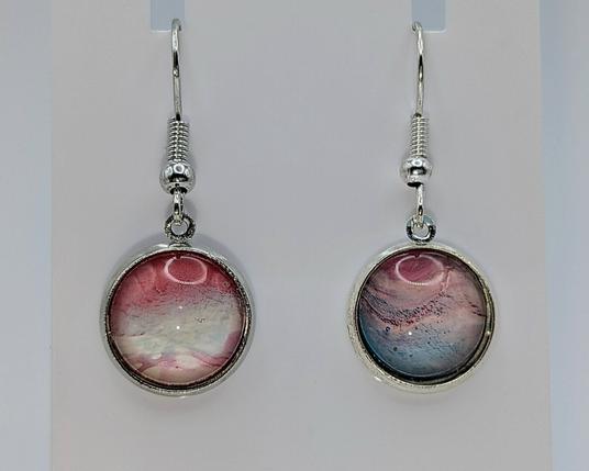 A pair of paint dip earrings: the settings are silver, and the dipped cabochons are shades of pink, turquoise, and white.