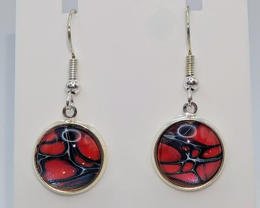 A pair of paint dip earrings: the settings are silver, and the dipped cabochons are red, navy blue, and white.