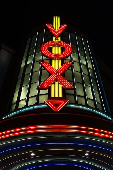 Close-up on the tower of splendid Art Deco style Cine vox cinema in Strasbourg at night, decorated by a giant Vox logo illumitated in red and place on a yellow neon arrow.