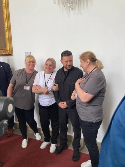Quando Zelensky era a Praga, notò le pulizie ucraine che sbirciavano attraverso la divisione del vetro. Li ha invitati per una foto.
