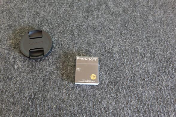 ProGrade SDXC package (256GB) next to a Lumix lens cap.