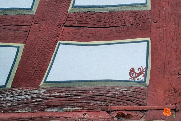 Detail an einem Fachwerkhaus,  ein kleiner brauner Vogel auf weißer Füllung