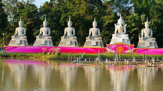 Row of Buddha statues on lake.