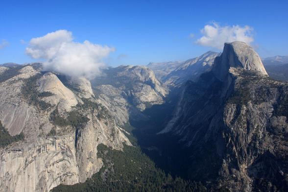 The eastern end of Yosemite Valley, with Half Dome under blue skies with a few small, low puffy clouds.