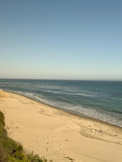 Picture of a cove alongside the train with waves rolling up onto the sand.