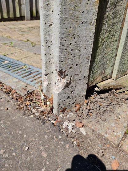 base of concrete post showing damage and concrete chips