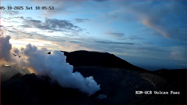Cráter activo del Volcán Poás, con atardecer en el horizonte y la característica pluma blanca de gases volcánicos.