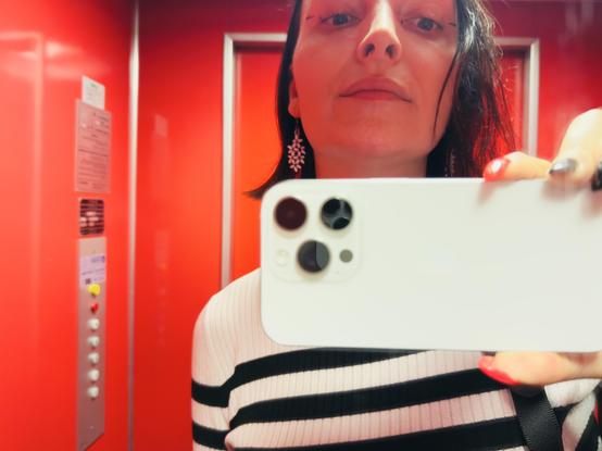 Me in a very red elevator, reflected in its mirror. I did one of dots and ticks eyeliner makeup things. Hair messier than usual!