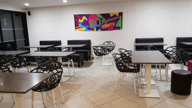 A room set up for an 80s party, with tables, chairs, and a themed banner.