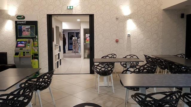 An indoor shot of tables and chairs in a room with patterned wallpaper and a doorway leading to another area.