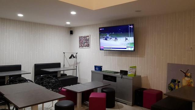 A small restaurant with tables, booths, a TV, and a bar.