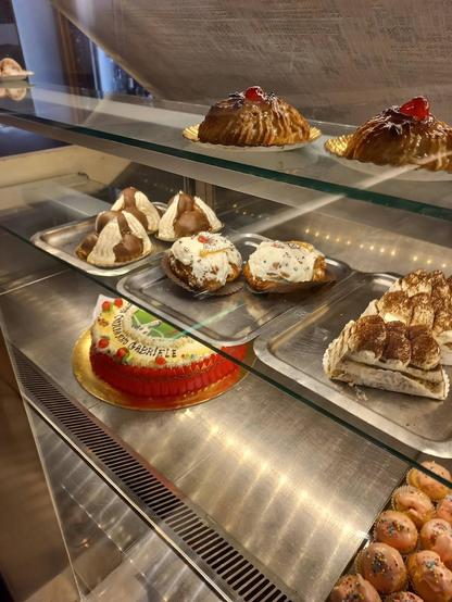 A glass display case is filled with assorted pastries and cakes.