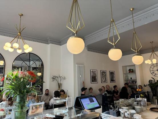 A bright cafe interior with stylish lighting fixtures and customers.