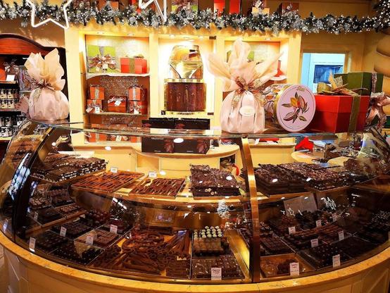 A chocolate shop display case filled with various chocolates and treats, decorated for the holidays.