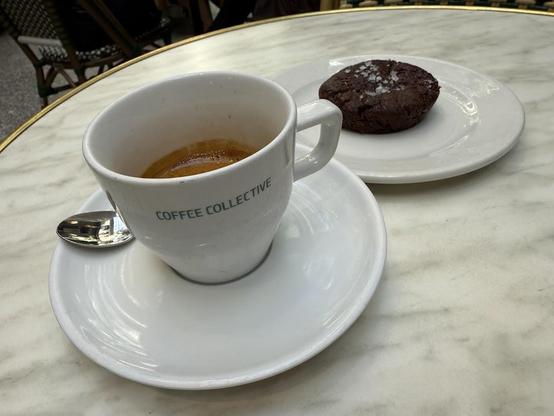 A cup of espresso on a saucer next to a brownie on a plate.