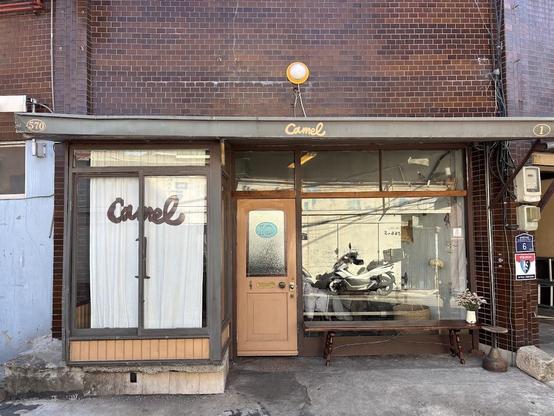 A charming storefront with "Camel" signage. It has a brick facade and a vintage aesthetic.