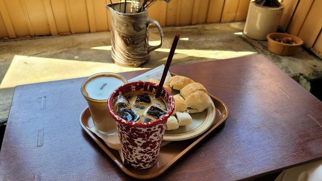 A tray with two drinks and bread on a wooden table.