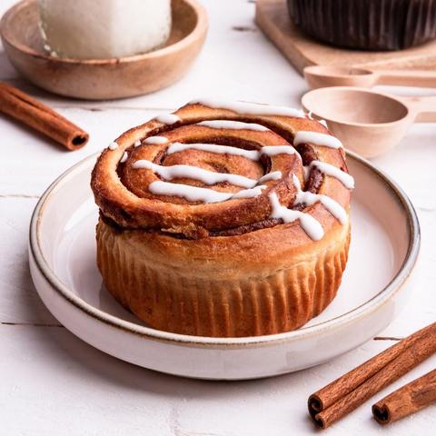 A cinnamon roll with white icing on a plate.