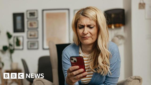 Blonde woman looks frustrated while using her smartphone at home